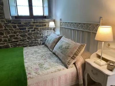 a bedroom with a bed with a stone wall at Apartamentos Rurales Ca Lulón in Navelgas