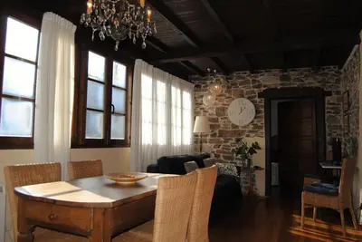 a dining room with a table and a stone wall at Apartamentos Rurales Ca Lulón in Navelgas