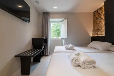 a hotel room with two beds and a window at Ultreia Seven Rooms by Adeloló in Santiago de Compostela