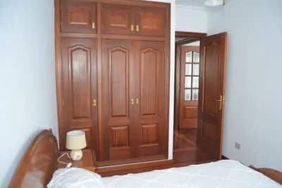a bedroom with wooden doors and a bed in a room at Precioso apartamento de 3 habitaciones en Cabañas. in Cabañas