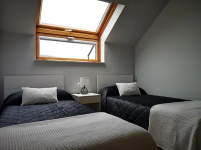 a attic room with two beds and a window at Alojamientos Viveiro - Ático Playa de Covas in Viveiro
