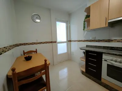 a kitchen with a table and a clock on the wall at Alojamientos Viveiro - Ático Playa de Covas in Viveiro