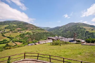 a small village on a green hill with a clock tower at Apartamentos Casa Paulino in Taramundi