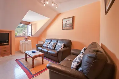 a living room with a leather couch and a table at Apartamentos Casa Paulino in Taramundi