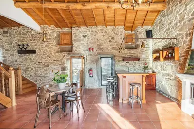 a kitchen with a table and chairs and a stone wall at A Casa Romeu in Santiago de Compostela