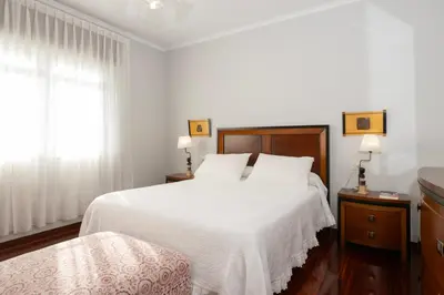 a white bedroom with a large bed and a window at Casa Jesús in A Capela