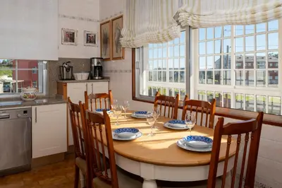 a kitchen with a wooden table with chairs and a dining room at Casa Jesús in A Capela