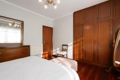 a bedroom with a bed and wooden cabinets and a chair at Casa Jesús in A Capela