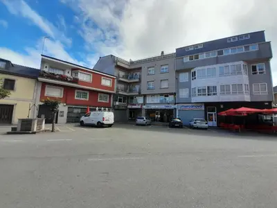 a building with cars parked in a parking lot at Apartamento a Carballeira in Lugo