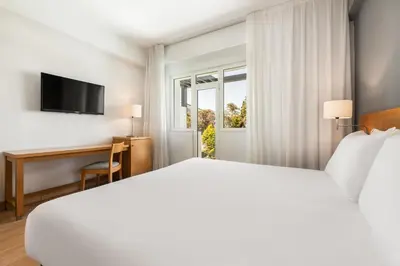 a hotel room with a bed and a desk and a window at Exe Peregrino in Santiago de Compostela