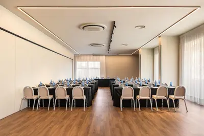 a conference room with rows of tables and chairs at Exe Peregrino in Santiago de Compostela