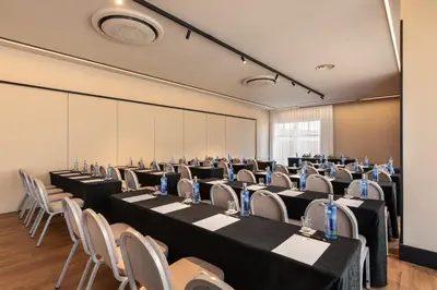 a conference room with rows of tables and chairs at Exe Peregrino in Santiago de Compostela
