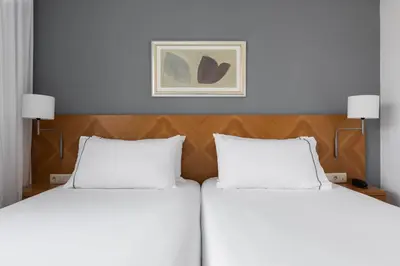 two beds in a hotel room with a picture on the wall at Exe Peregrino in Santiago de Compostela