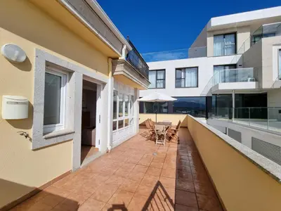 a balcony of a building with chairs and an umbrella at Terrazas del Cantábrico in Foz