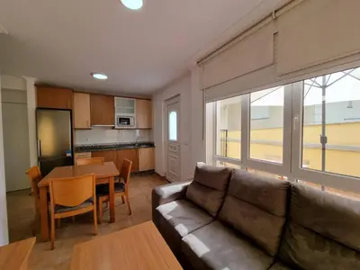 a living room with a couch and a table and a kitchen at Terrazas del Cantábrico in Foz