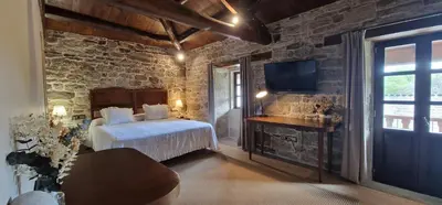 a bedroom with a bed and a tv in a room at Habitaciones La Cuevona de Guitiriz,Parga, en el camino norte Lugo in Parga