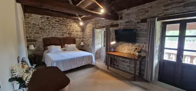 a bedroom with a bed and a tv in a room at Habitaciones La Cuevona de Guitiriz,Parga, en el camino norte Lugo in Parga