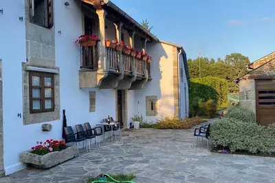 a building with a balcony with chairs and a table at Habitaciones La Cuevona de Guitiriz,Parga, en el camino norte Lugo in Parga