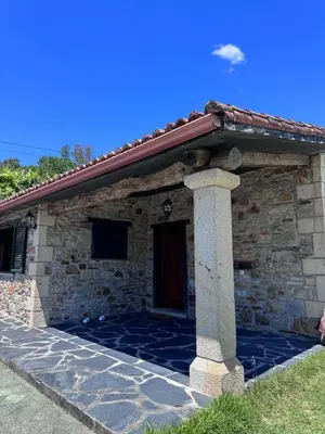 a stone building with a door and a pillar at Casa 2 habitaciones con piscina y cenador al aire libre in Pontevedra