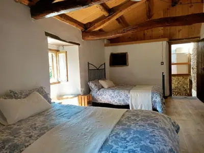 two beds in a room with wooden ceilings at Granja Labrada: Alojamiento con caballos in Santa María
