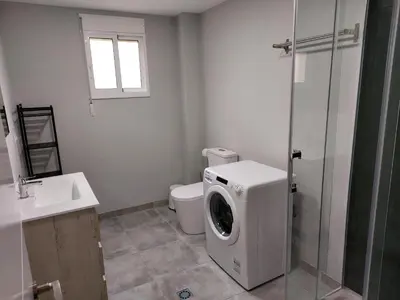 a bathroom with a washing machine and a toilet at Apartamento Vistas Pedrido in Paderne