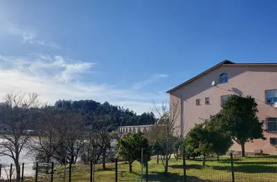 a building with a fence next to a body of water at Apartamento Vistas Pedrido in Paderne