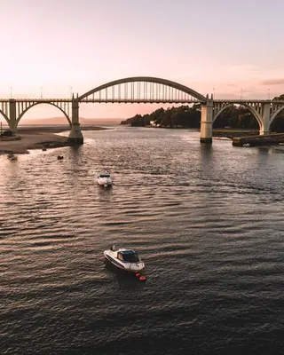 a boat in the water in front of a bridge at Apartamento Vistas Pedrido in Paderne