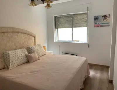 a bedroom with a large bed with a window at PISO PLAYA SAN CIPRIÁN (MARIÑA LUCENSE) in San Ciprián