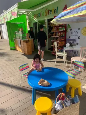 a little girl sitting at a blue table in front of a store at PISO PLAYA SAN CIPRIÁN (MARIÑA LUCENSE) in San Ciprián