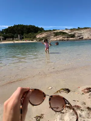 a person withsung glasses on the beach with a girl in the water at PISO PLAYA SAN CIPRIÁN (MARIÑA LUCENSE) in San Ciprián