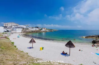 a beach with umbrellas and people in the water at PISO PLAYA SAN CIPRIÁN (MARIÑA LUCENSE) in San Ciprián