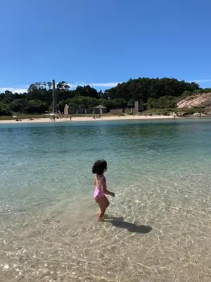 a little girl walking in the water on a beach at PISO PLAYA SAN CIPRIÁN (MARIÑA LUCENSE) in San Ciprián
