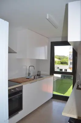 a white kitchen with a sink and a window at Precioso apartamento con garaje en Ares. in Ares