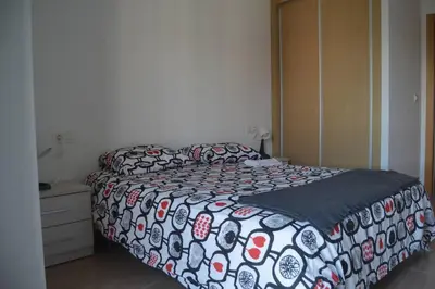 a bedroom with a bed with a black and white comforter at Precioso apartamento con garaje en Ares. in Ares