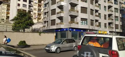 two cars parked on a city street with buildings at Apartamentos xistra in Cangas del Narcea