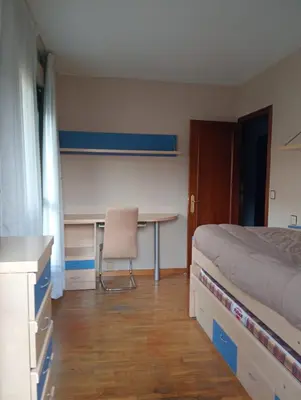 a bedroom with a bed and a desk and a table at Apartamentos xistra in Cangas del Narcea