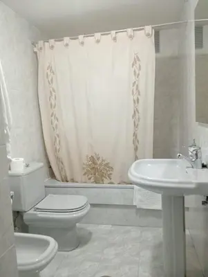 a white bathroom with a toilet and a sink at Apartamentos xistra in Cangas del Narcea