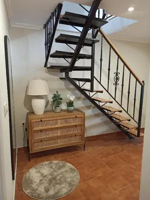 a spiral staircase in a living room with a table and a lamp at A casiña de Estela in Caldas de Reis