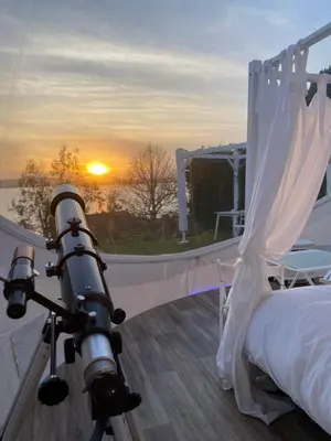 a camera on a balcony with a view of the sunset at Burbujas Astronómicas Albarari Coruña in Oleiros