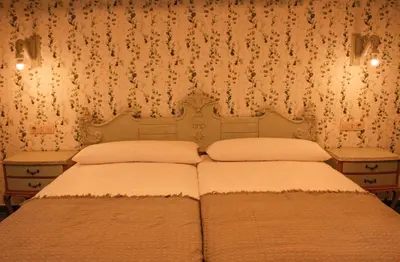 two beds in a bedroom with floral wallpaper at Casa Meiga in Arzúa