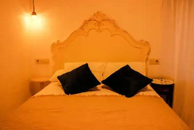 a white bed with two black pillows on it at Casa Meiga in Arzúa