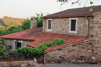 a stone house with a red roof at Casa Meiga in Arzúa