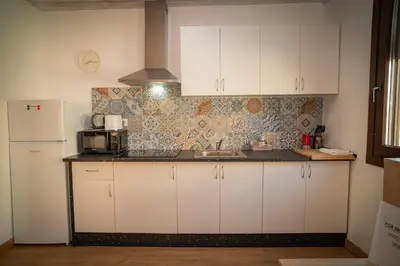 a kitchen with white cabinets and a sink and a refrigerator at O Lar do Camiñante in Palas de Rei