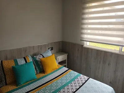a bedroom with a bed with colorful pillows and a window at Casa Icaro in Barreiros