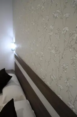 a bedroom with a bed and a wall with floral wallpaper at Baixo a Lua Rooming in Sarria