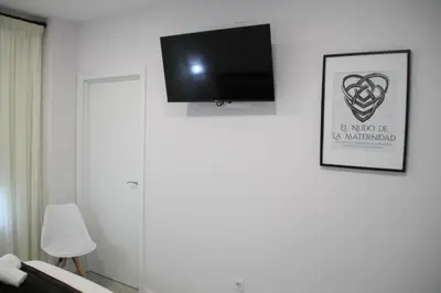 a room with a flat screen tv on the wall at Baixo a Lua Rooming in Sarria