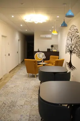 a waiting room with chairs and tables and a tree on the wall at Baixo a Lua Rooming in Sarria