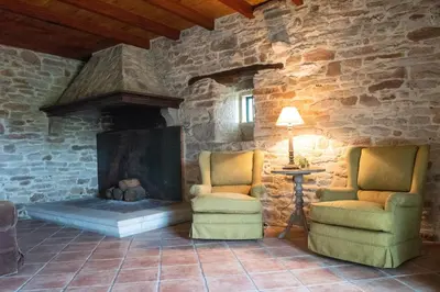a living room with two chairs and a fireplace at Casa Quinta de Cecil in Villalba