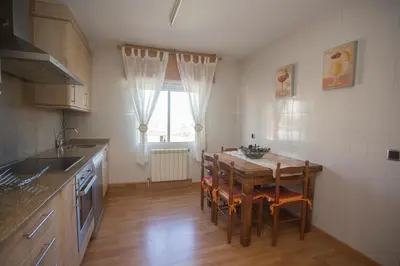 a kitchen with a table and chairs and a window at Apartamentos Sarela in Santiago de Compostela