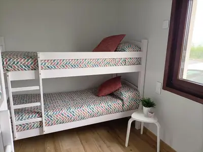 a room with two bunk beds and a chair at CASA DO LAGOEIRO in Boimorto
